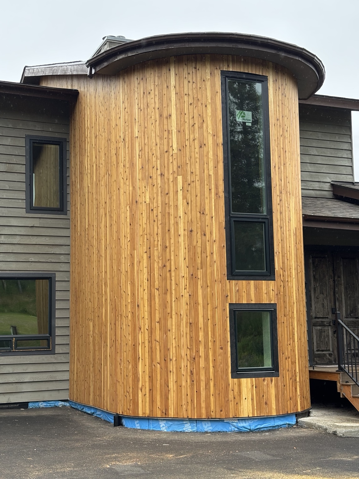 Custom curved exterior clad in vertical thermally modified wood siding with black-trim windows