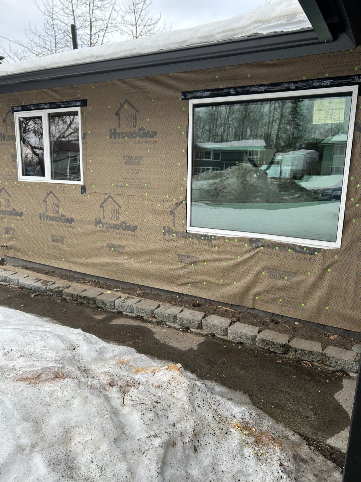 Drainable house wrap and properly flashed replacement windows before exterior siding