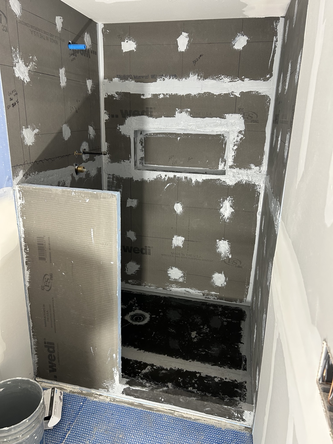 Wedi shower system with sealed seams, fasteners, niche, and waterproof shower base before tile